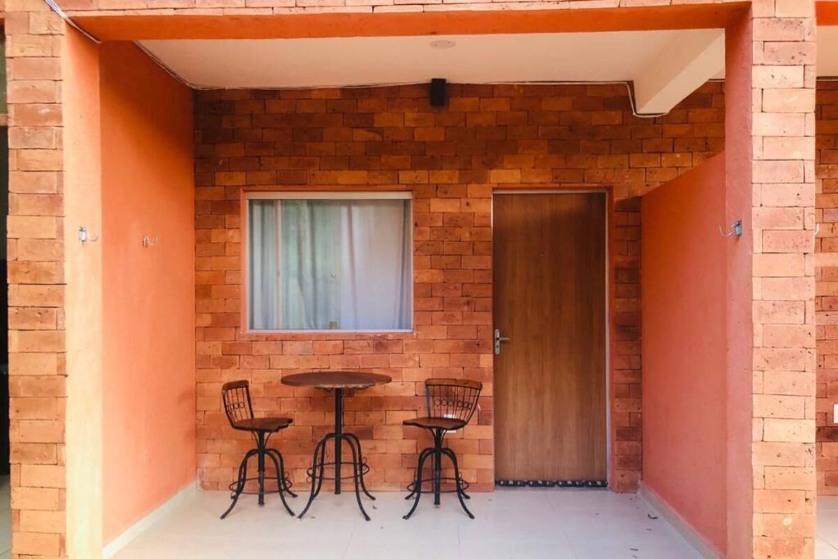 A small outdoor area with a brick wall, a wooden door, and a table with two chairs.