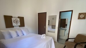 Una habitación de hotel con una cama grande, una silla, una puerta y un espejo.