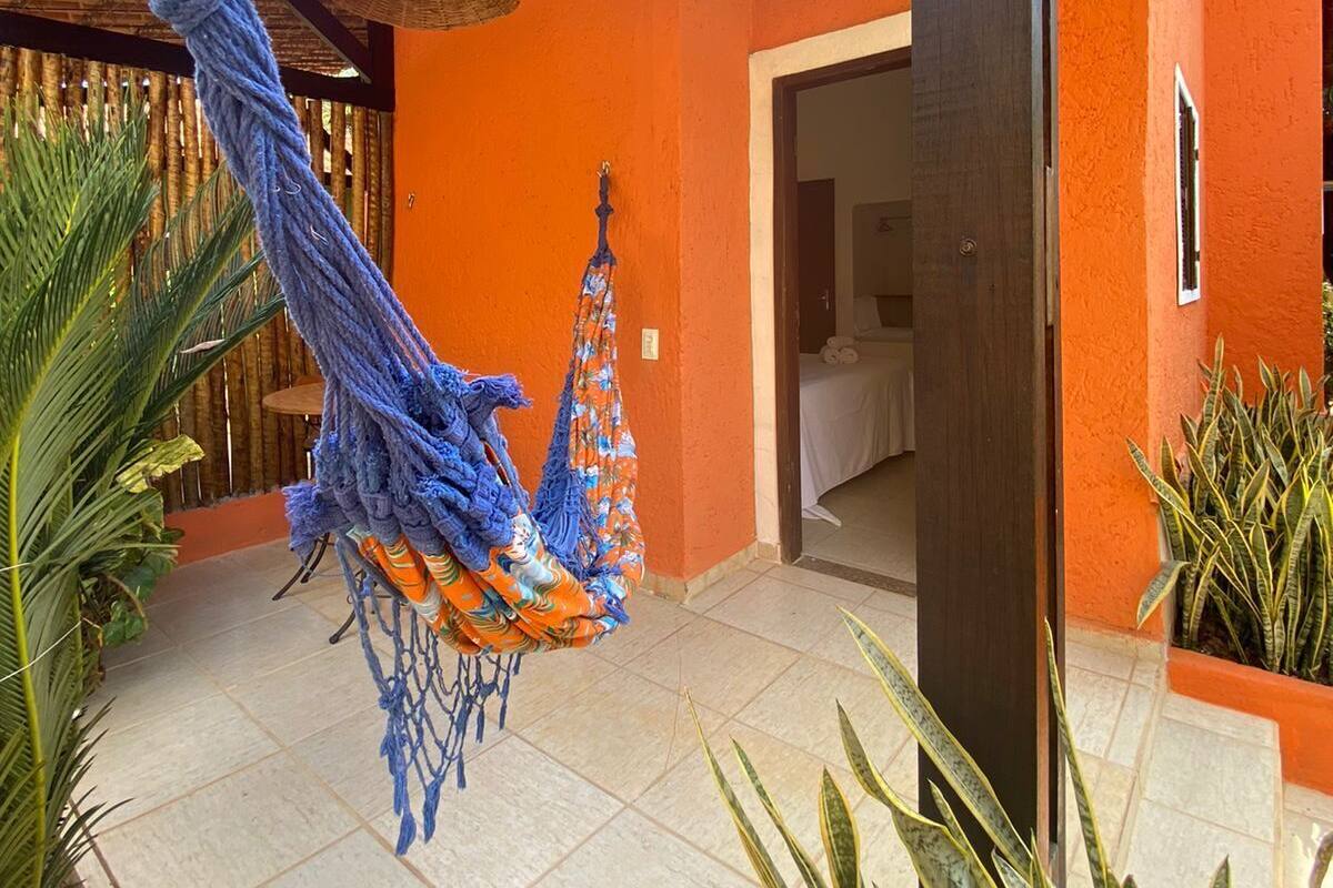 A room with a hammock, a bed, and a window.