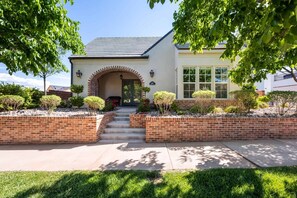 A two-story house with a brick entrance, a front porch, and a well-maintained garden.