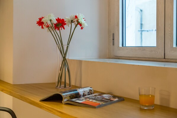 Une table en bois sur laquelle se trouvent un vase de fleurs, un magazine et un verre contenant une boisson.