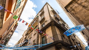 A narrow street with buildings, flags, and a blue banner.