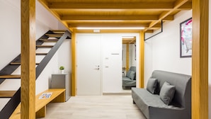A modern interior with a staircase, a grey sofa, and a wooden bench.