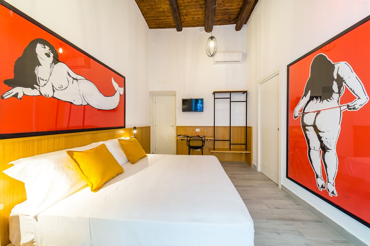 A hotel room with a large bed, a desk, and a TV.