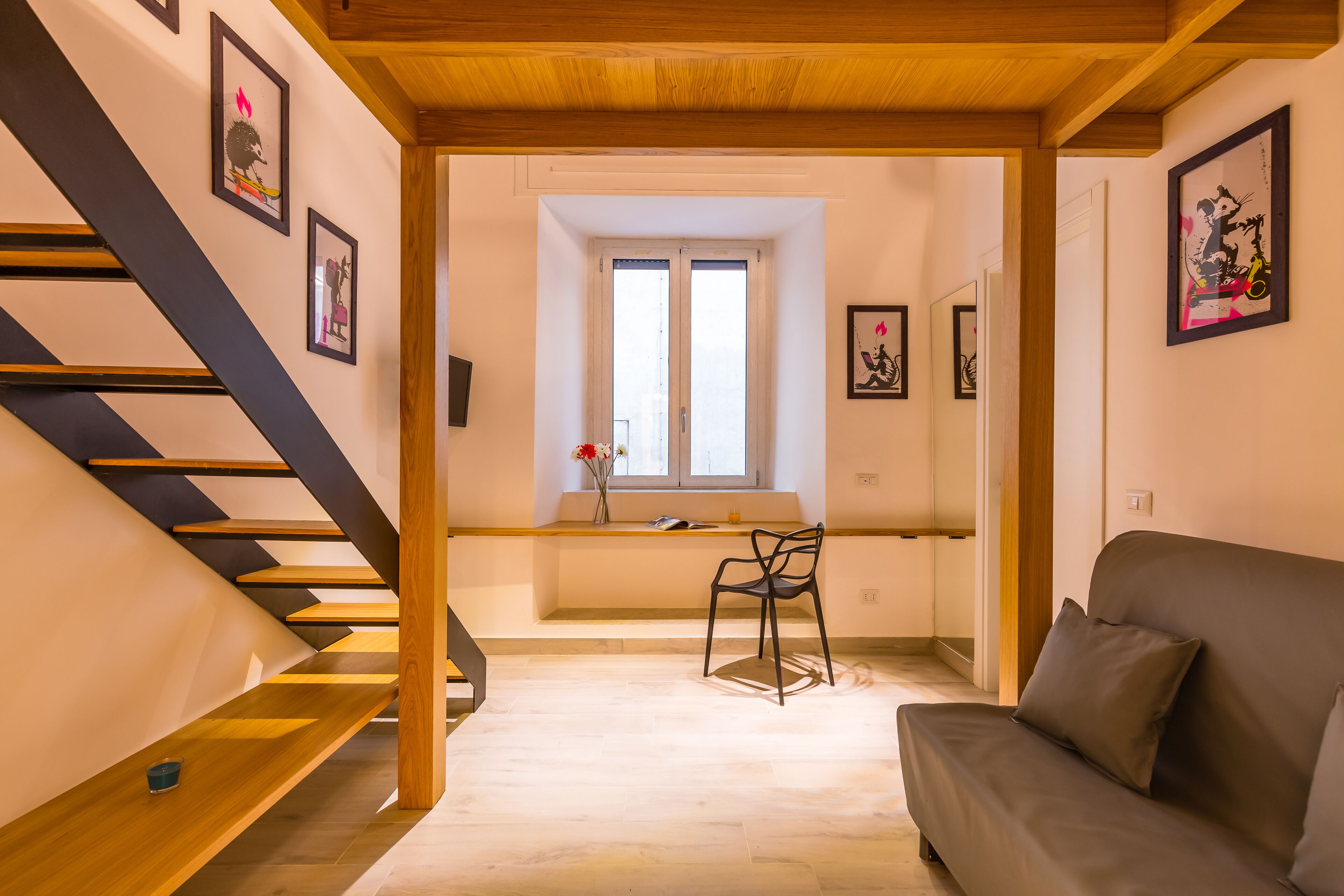 Un intérieur moderne avec un escalier, un canapé et des œuvres d’art accrochées aux murs.