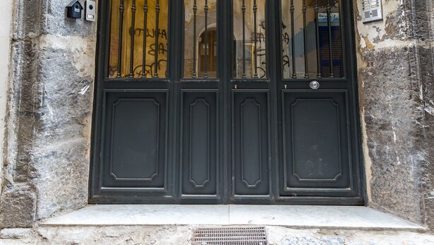 A black double door with a metal gate, a 'No Parking' sign, and a 'Passo Carrabile' sign above it.