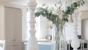 A white table with two white candle holders and a clear vase with greenery. - Arden House - Family Luxury in Lahinch! (Lahinch)