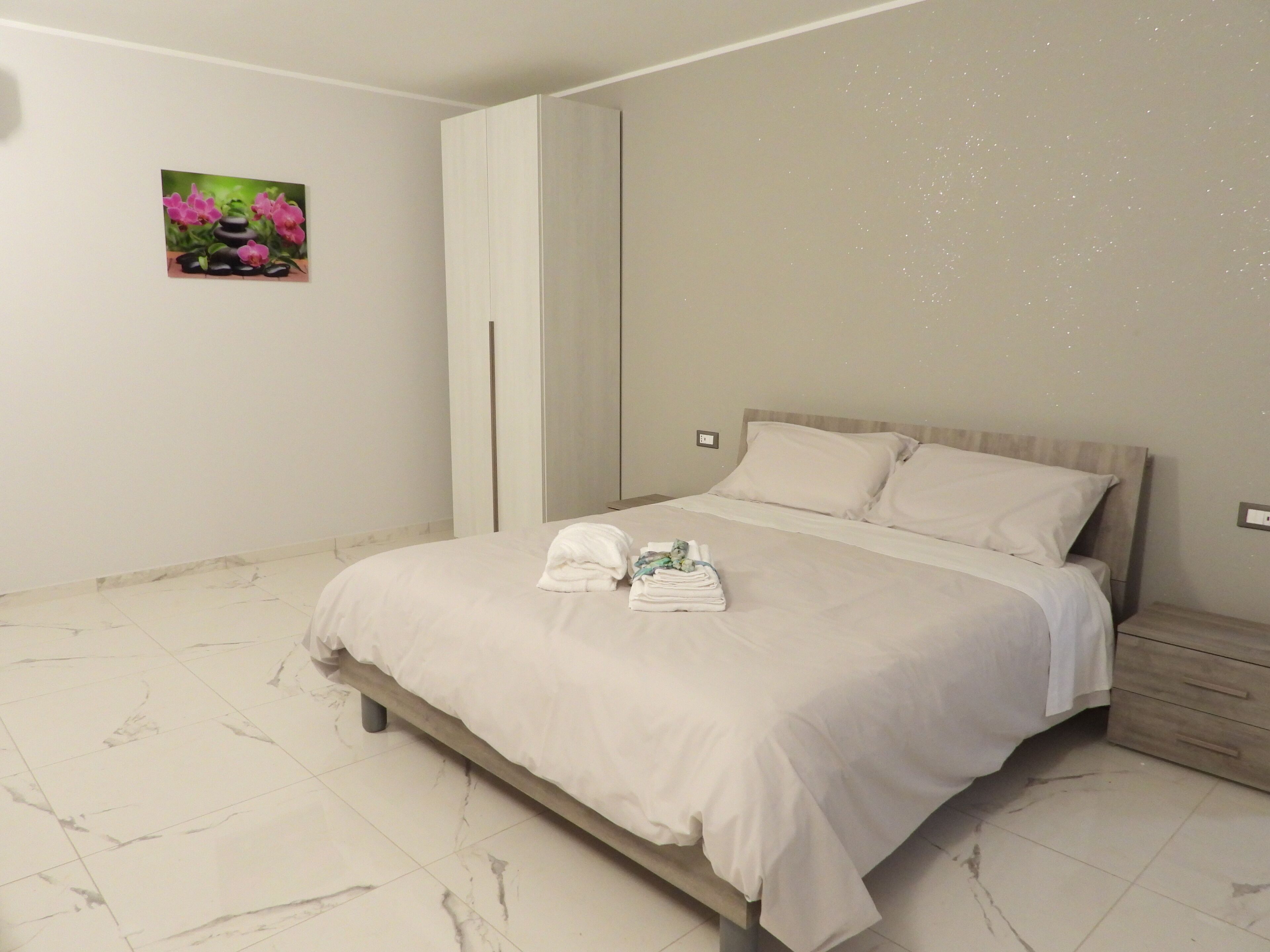 Une chambre à coucher avec un lit, une table de chevet, une armoire et un tableau au mur.