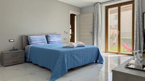 Une chambre à coucher comprenant un lit, une table de chevet, une commode et une salle de bain avec un lavabo et un miroir.