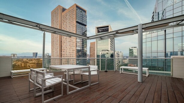 A rooftop terrace with a table and chairs, overlooking a cityscape with modern buildings. - Polanco 2BR  Skyline Balcony, Gym & Sauna (Mexico City)
