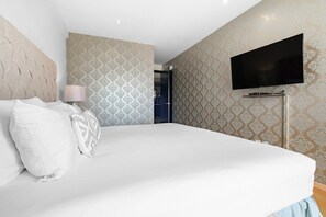 A bedroom with a bed, a television mounted on the wall, and patterned wallpaper.