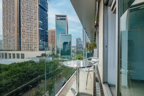 Un balcón con barandilla de vidrio que ofrece vistas a un paisaje urbano con edificios altos.