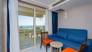 A balcony with a blue sofa, a wooden chair with an orange cushion, and a small round table.