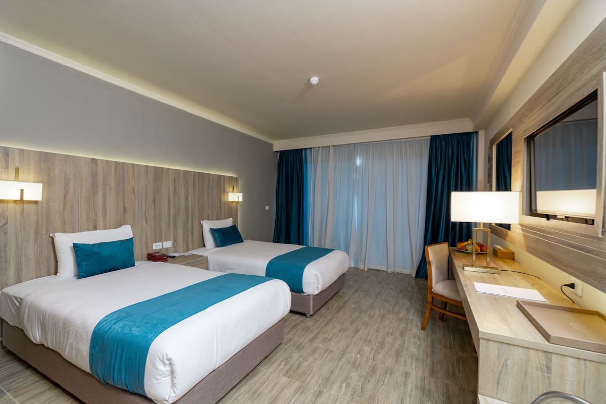 A hotel room with two beds, a desk, and a chair.