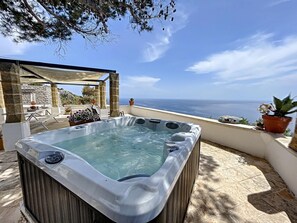 A hot tub on a terrace with a view of the sea.