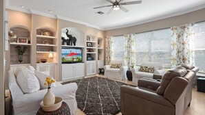 Ein Wohnzimmer mit Fernseher, Sofas, einem Couchtisch und Dekoration.