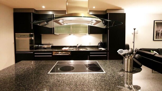 Una cocina moderna con una isla central, horno integrado y electrodomésticos de acero inoxidable.