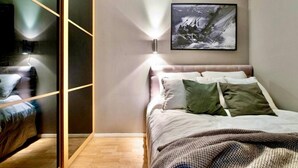 A bedroom with a bed, a wall-mounted light, and a framed picture. - Løkka City Apartments (Oslo)