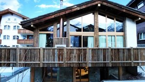 Un pontile in legno con una struttura di un edificio moderno, ampie finestre e un camino visibile.