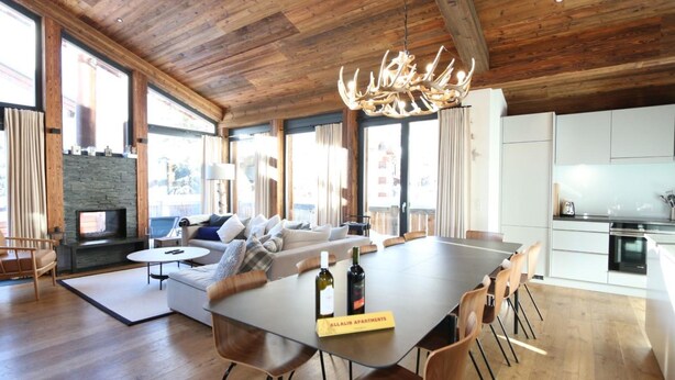 Un'ampia zona giorno con un grande tavolo da pranzo in legno, un divano e un camino.