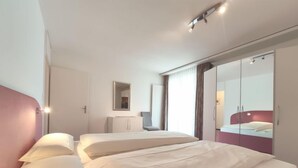 A modern hotel room with two beds, a wardrobe, and a mirror. - Attika Wohnung Allod Park Haus C 801 by Interhome (Davos)