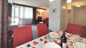 A dining area with a table set for four, red chairs, and a chandelier. - Attika Wohnung Allod Park Haus C 801 by Interhome (Davos)