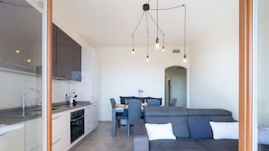 A modern kitchen with a built-in oven and a dining area with a gray sofa and a table.
