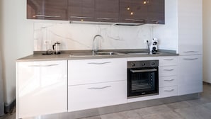 A modern kitchen with a marble backsplash, stainless steel appliances, and a combination of white and dark wood cabinetry.