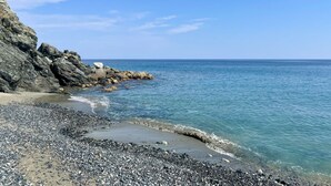 A rocky beach with clear blue water and a calm sea.