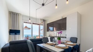 A modern living room with a sofa, dining table, and kitchen area.