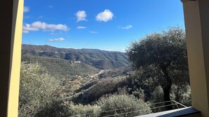A view through an arched window of a mountainous landscape with scattered buildings. - Casa Norvegia by Interhome (Valloria)