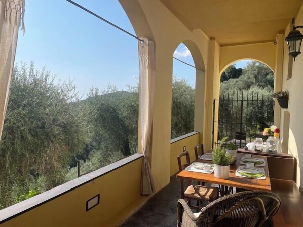 Ein Balkon mit Tisch für zwei Personen, mit Blick auf eine üppige Landschaft.