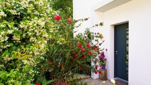 A garden with various plants and flowers, a wooden bench, and a door. - Chemin du Ruisseau d'Arcangues by Interhome (Anglet)