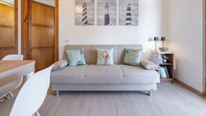 A modern living room with a grey sofa, wooden door, and three lighthouse paintings on the wall. - Il Faro Blu by Interhome (Villasimius)
