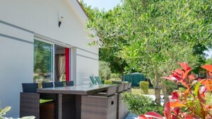 A modern outdoor patio with a glass-top table and wicker furniture.
