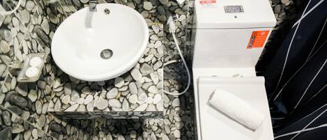 Un baño con lavamanos blanco, inodoro y cartel informativo.