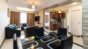 A modern living room with a dining area, a kitchen, and a separate bathroom. - Pacific Bay Grand Suites (Manila)