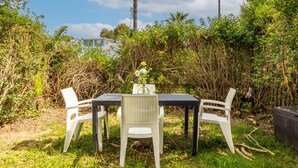 Un espace de restauration en plein air, avec une table et des chaises, entouré d’une végétation luxuriante et de palmiers.