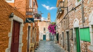 Una stretta strada acciottolata fiancheggiata da edifici in pietra con balconi e persiane.