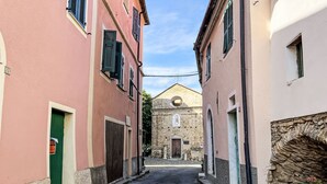 A narrow street flanked by buildings with stone facades and a church in the background. - Casa Sylvie by Interhome (Lucinasco)
