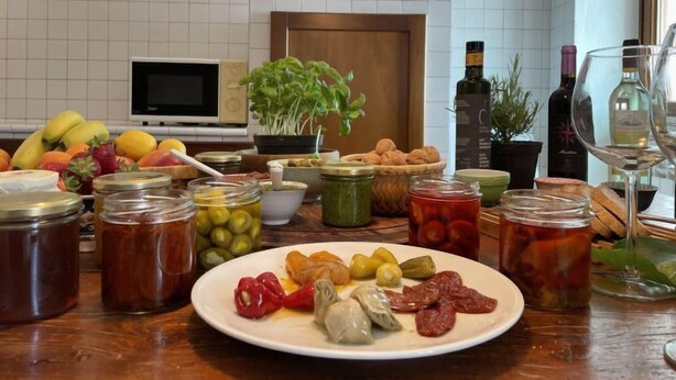 A kitchen with a variety of food items, including fruits, vegetables, and condiments. There is a microwave, a potted plant, and a hanging pot. - Casa Sylvie by Interhome (Lucinasco)