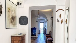 A hallway with a wooden cabinet, a framed artwork, and a chair. - Casa Sylvie by Interhome (Lucinasco)