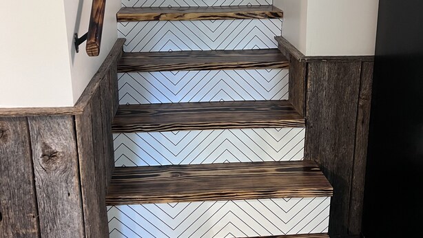 Een trap met houten treden en een muur met een herringbone patroon.