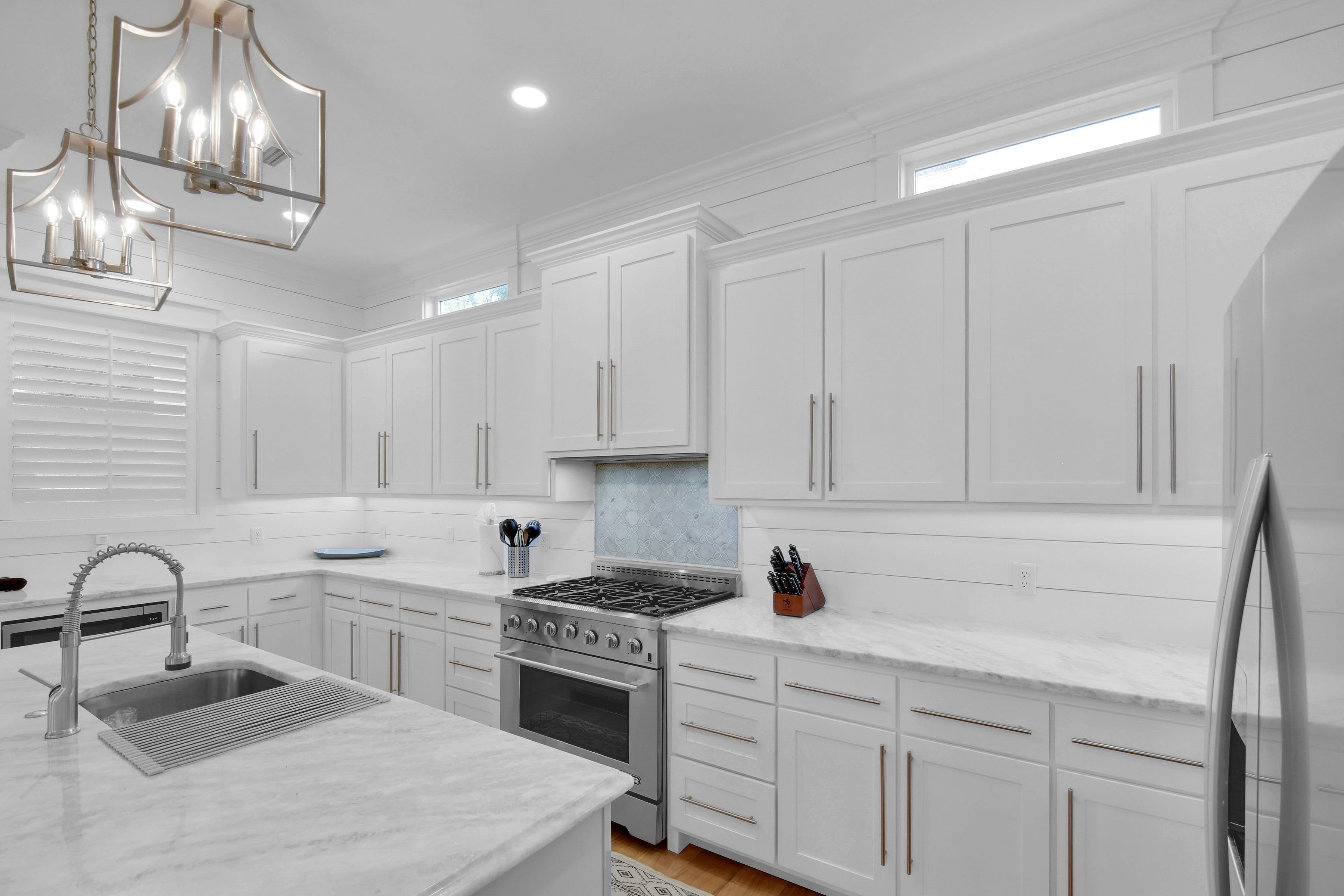 A modern kitchen with white cabinetry, a stainless steel range, and a built-in sink.
