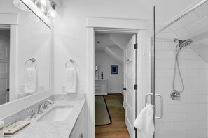 A modern bathroom with a marble sink, a large mirror, and a shower with a handheld showerhead. - Large Heated Pool • Walk to Restaurants • 2 King Ensuites • EV Charger (St Simons)