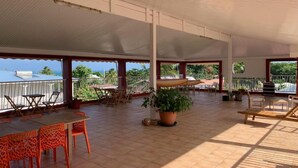 An outdoor patio area with a covered roof, outdoor furniture, and potted plants. - Les plages de Macabou (Le Vauclin)