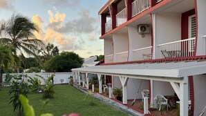 A two-story building with balconies, a covered outdoor seating area, and a well-maintained lawn. - Les plages de Macabou (Le Vauclin)