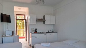 A hotel room with two beds, a kitchenette, a TV, and a balcony. - Les plages de Macabou (Le Vauclin)