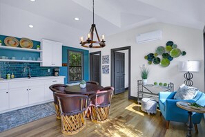A modern kitchen with white cabinets, a blue backsplash, and a dining area with a round table and chairs. - Terlingua at the Bend I Wimberley, seclusion, views (Wimberley)