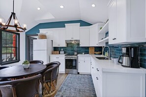 A modern kitchen with white cabinets, a stainless steel stove, and a coffee maker. - Terlingua at the Bend I Wimberley, seclusion, views (Wimberley)